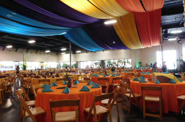 Colorful tiki event with round tables and chairs in Hall A