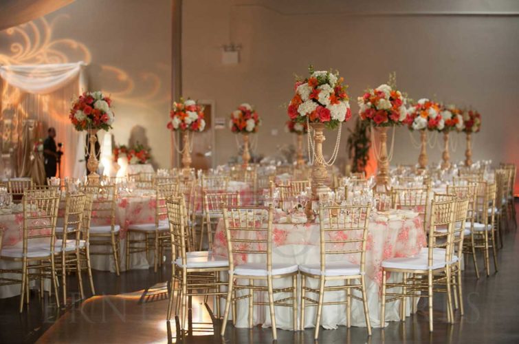 Wedding reception with flowers, beautiful table settings and chairs.