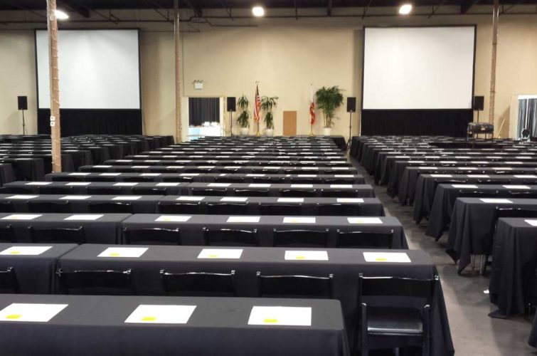 Expo hall with tables, chairs, and projection screens