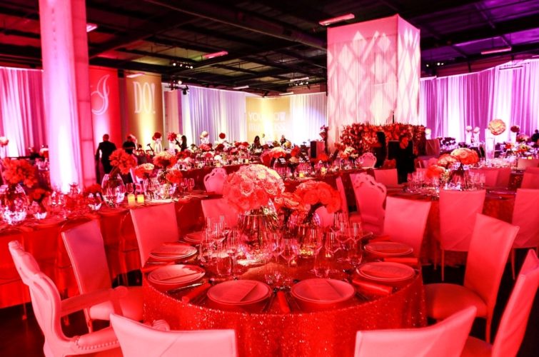 flowers and plates setting on the tables with chairs in red lighting at TSE Wedding Gala 2015
