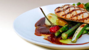 Grilled chicken with vegetables and sauce on a white plate 