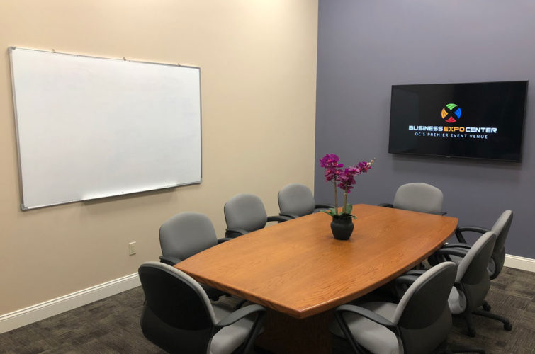 corporate/ executive meeting room with table, flowers, whiteboard, and tv